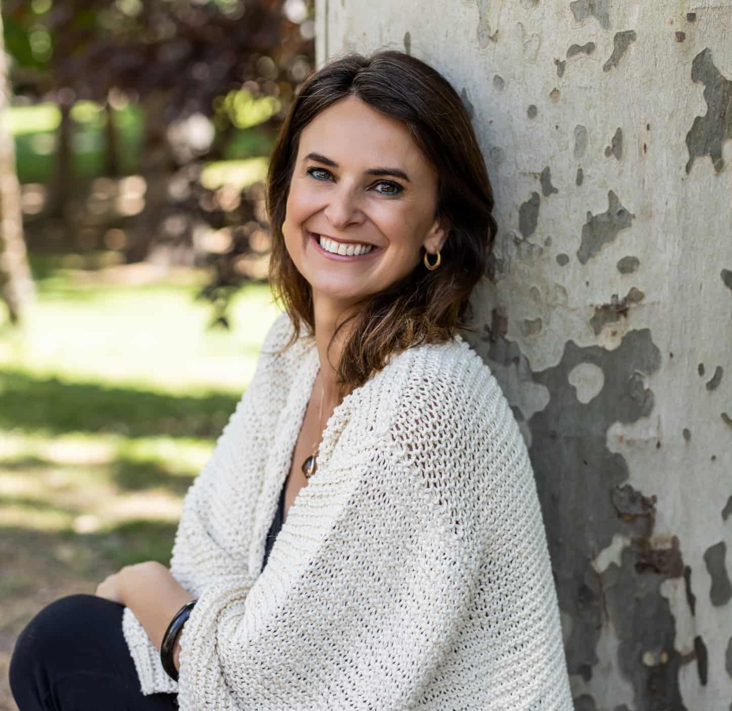 Thais Baldasso, proprietária da Agência Receptiva Thais Baldasso na Espanha, sorrindo no parque em um dia ensolarado no verão europeu.
