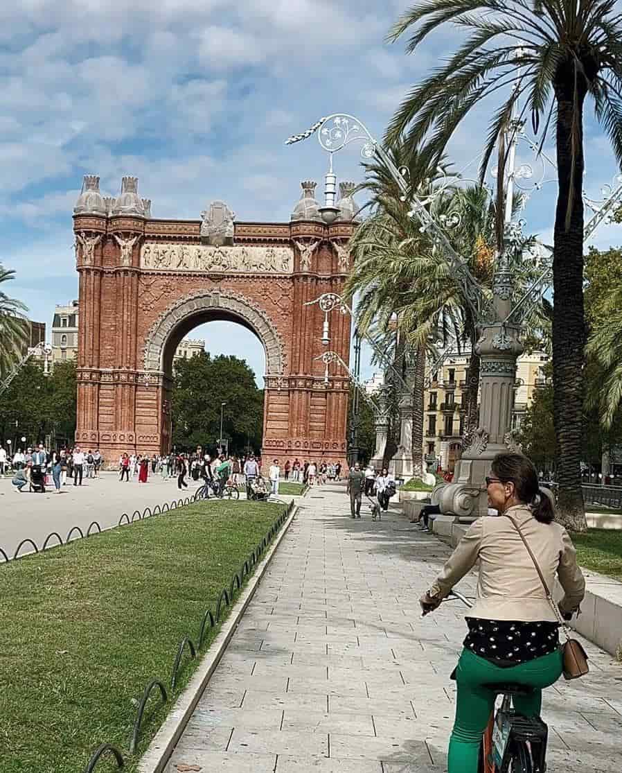 Mulher alegre andando de bicicleta por Madrid em um dia ensolarado.